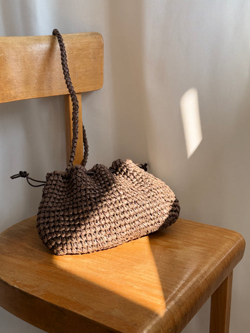 pouch von arc bags in braun. sie hängt an einer Stuhl lehne. 