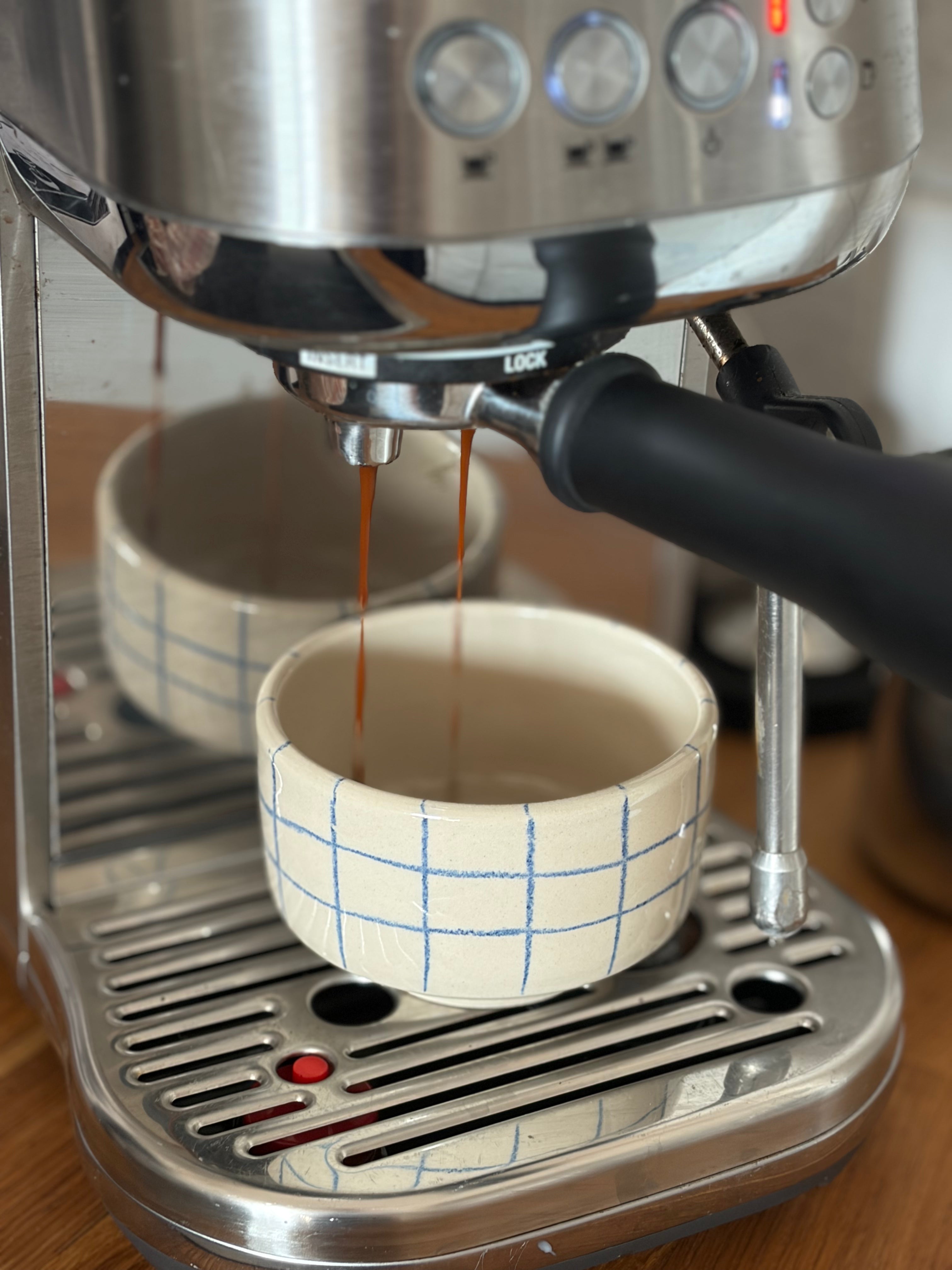 Handgedrehte Keramikbecher blau kariert, Espresso läuft aus der Siebträgermaschine ein