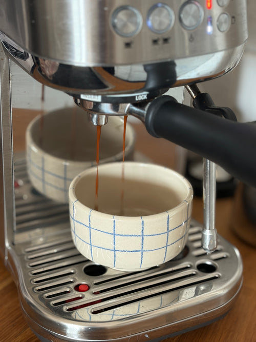 Handgedrehte Keramikbecher blau kariert, Espresso läuft aus der Siebträgermaschine ein