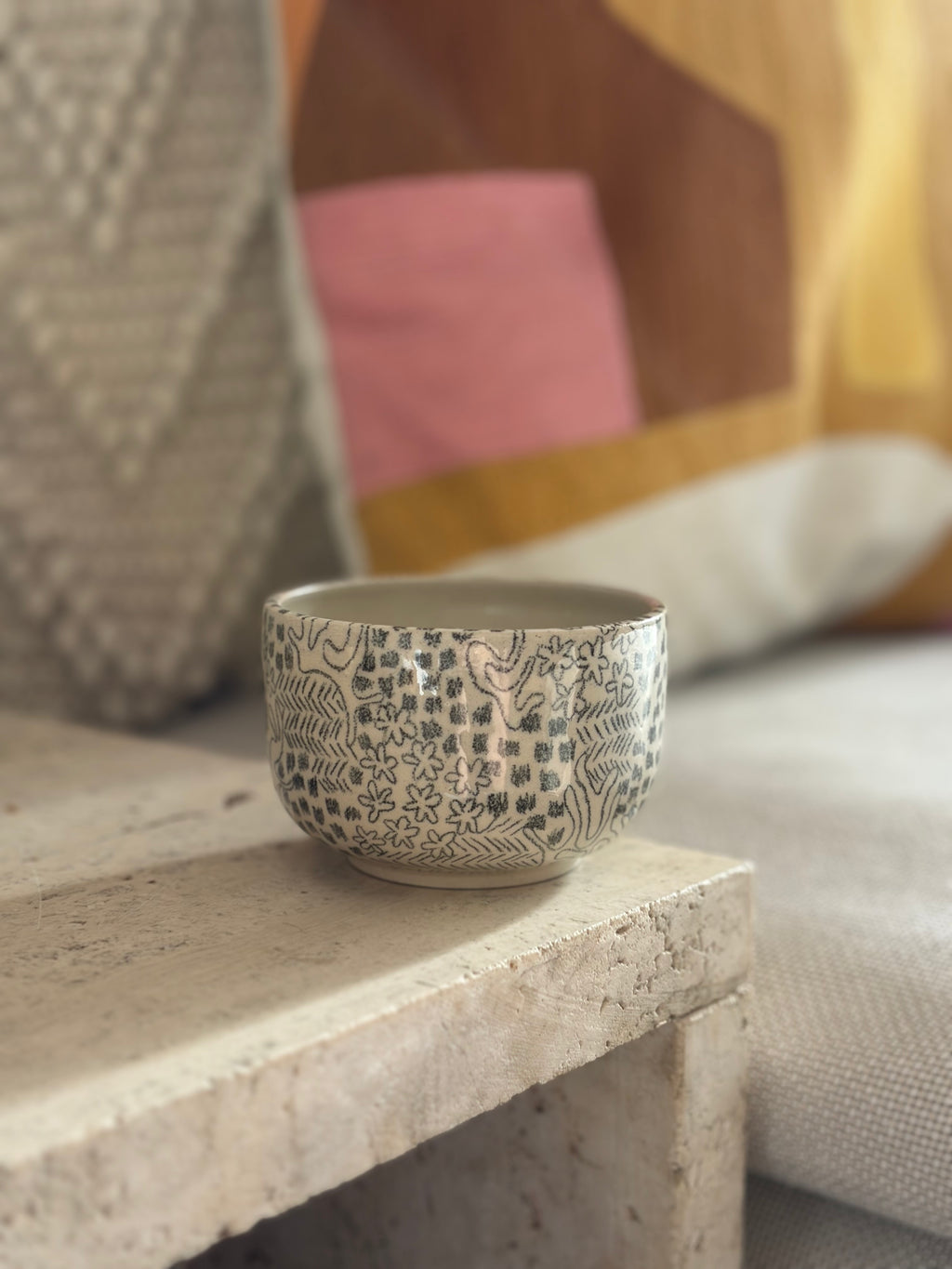 Handgedrehter Keramikbecher mit schwarzem gemaltem Muster in Sofaecke 