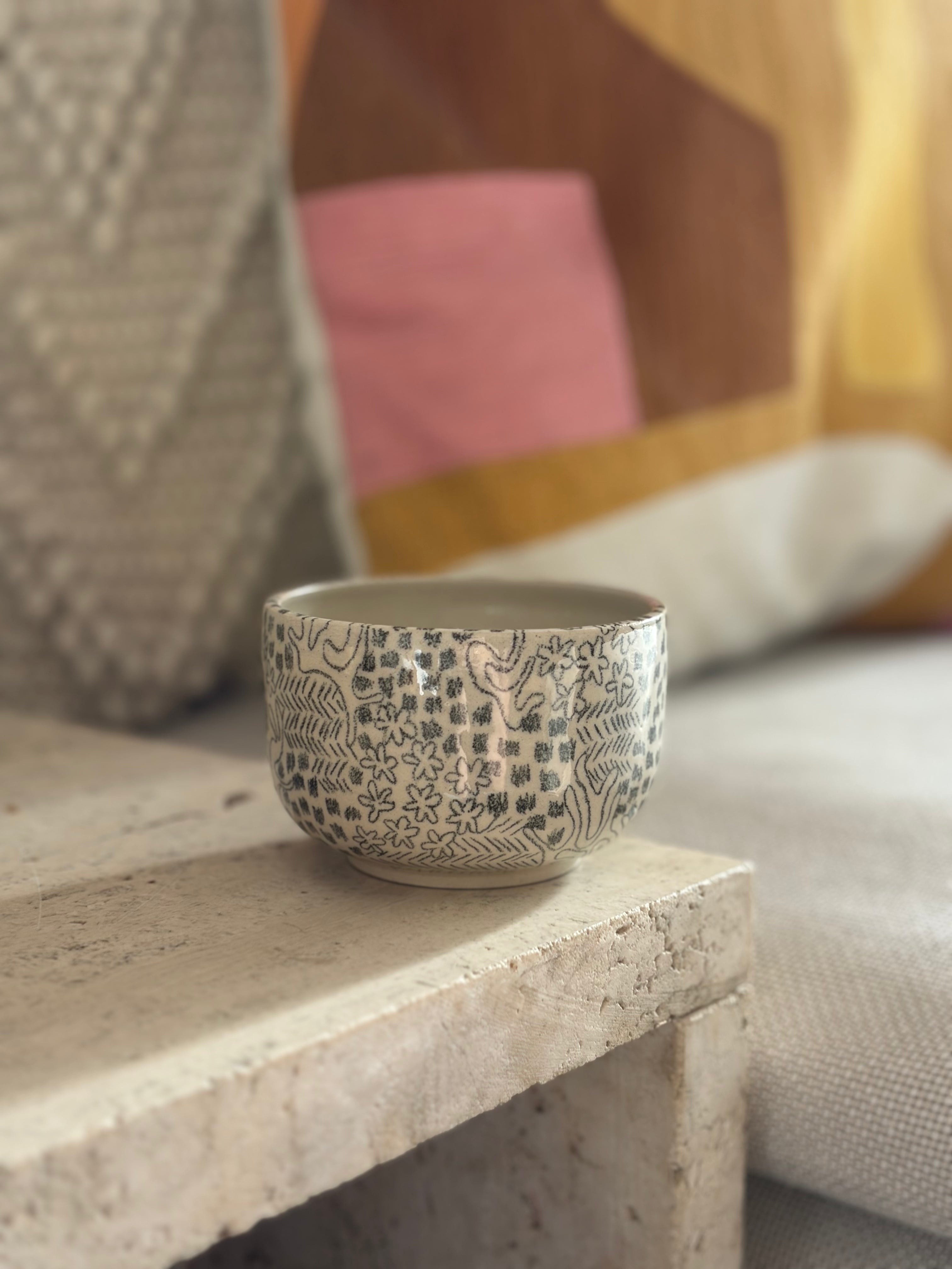 Handgedrehter Keramikbecher mit schwarzem gemaltem Muster in Sofaecke 
