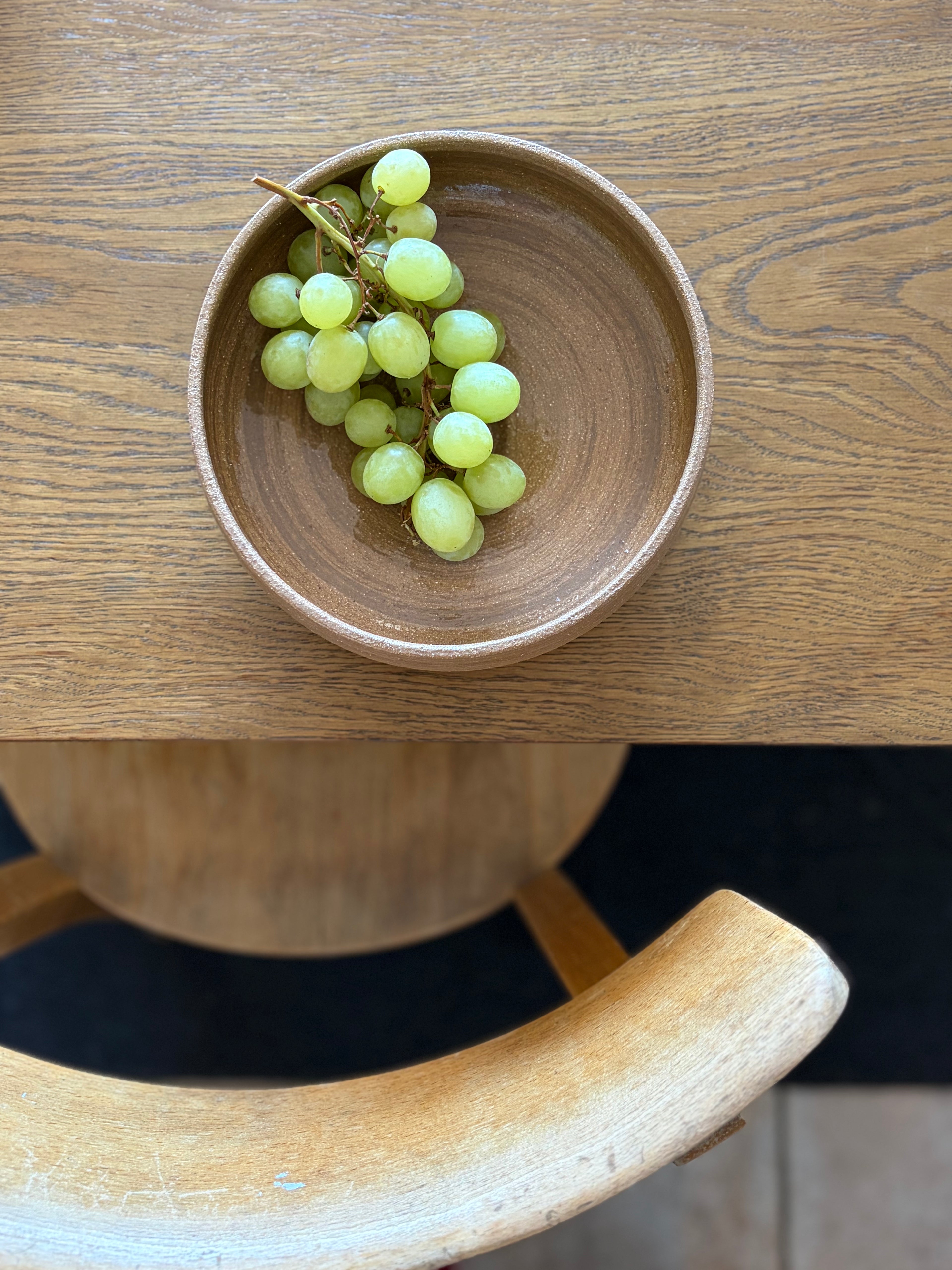 Handgedrehte Keramikschale Everyday Bowl von project.void._ mit grünen Weintrauben, Vogelperspektive auf Holztisch