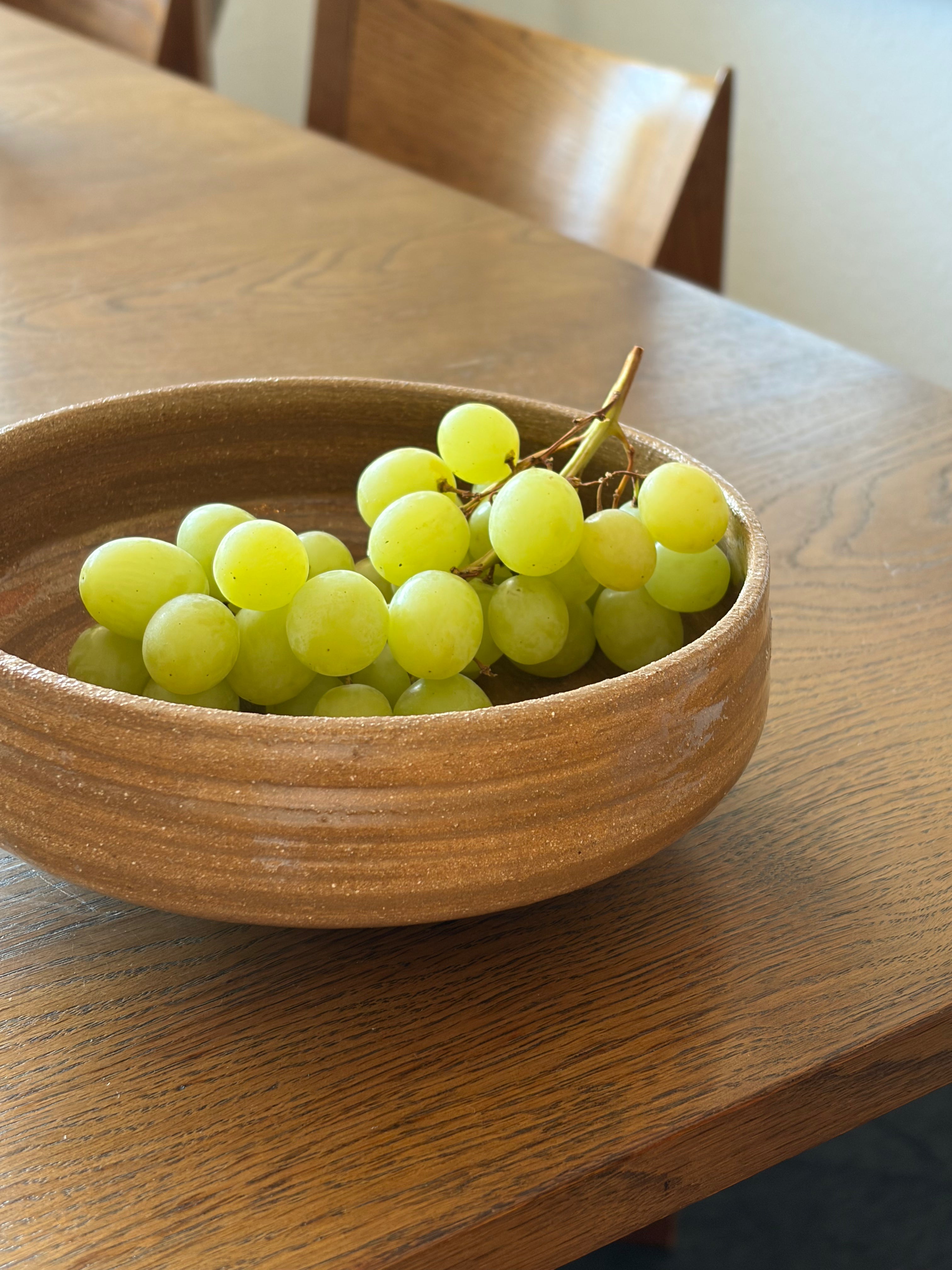 Handgedrehte Keramikschale Everyday Bowl von project.void._ mit grünen Weintrauben, auf Holztisch