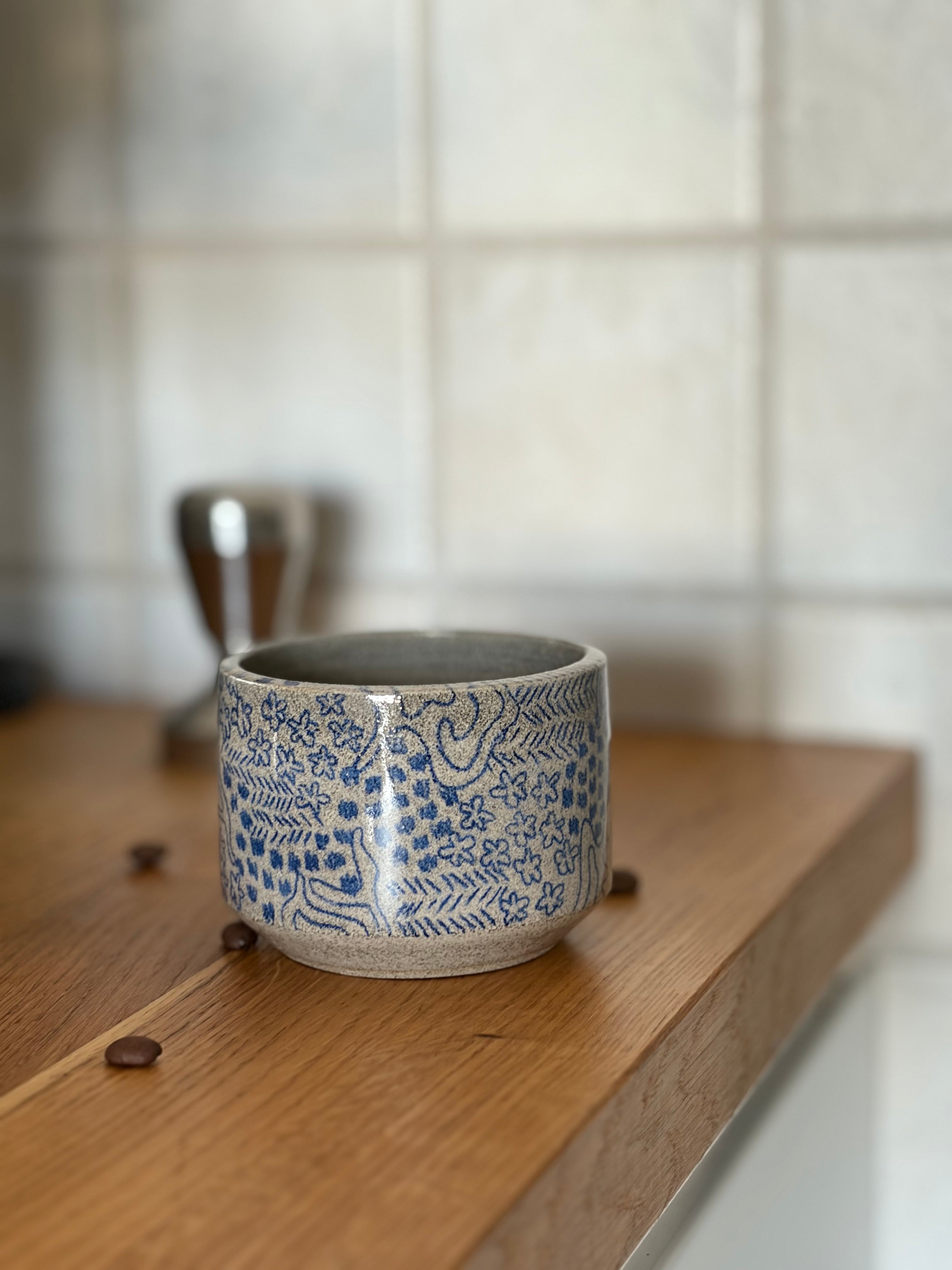 Handgedrehter Keramikbecher aus grauem Betont Ton, bemalt mit einem blauem Muster 