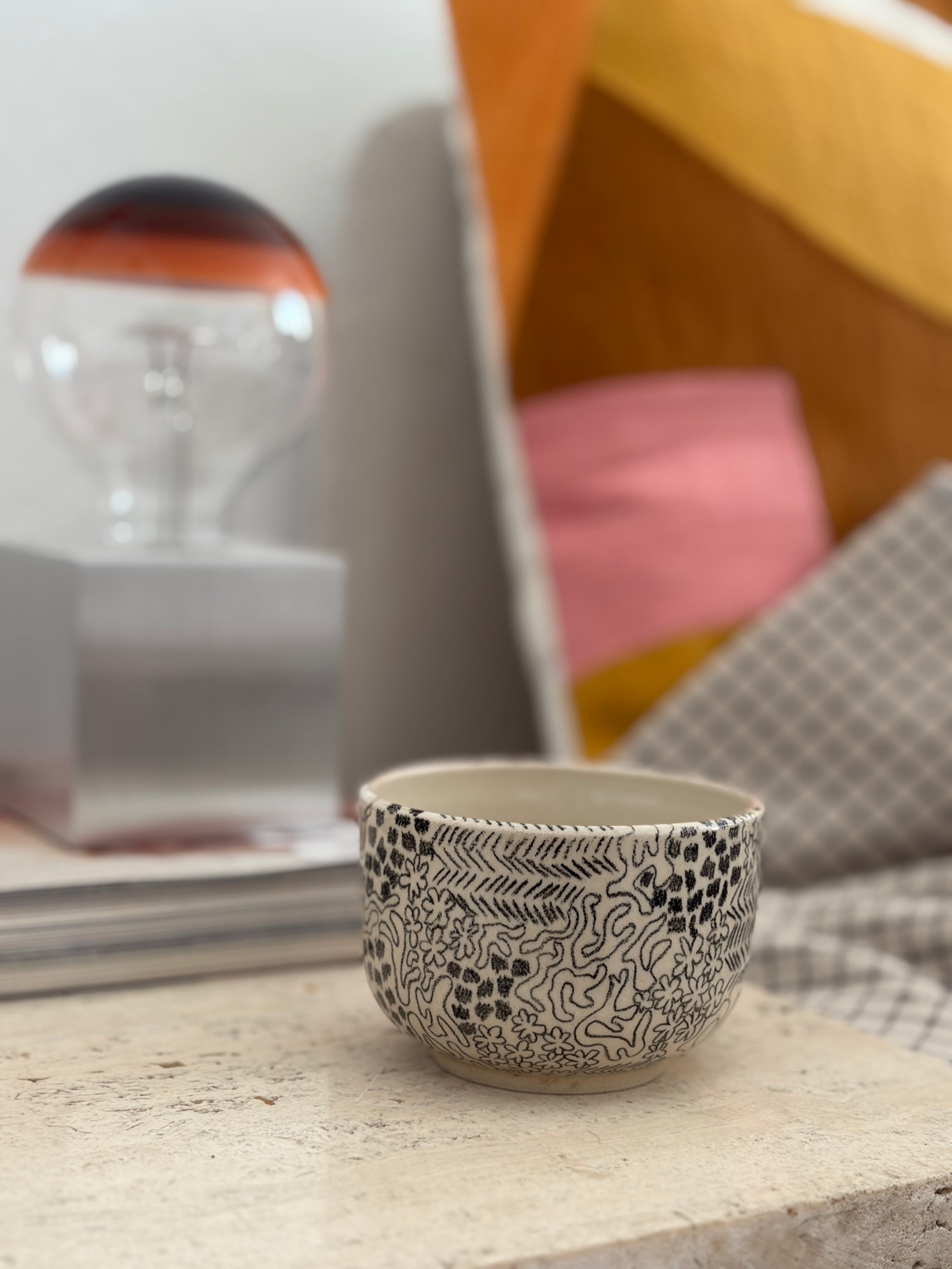 handgemachter Keramikbecher mit gemaltem Muster.