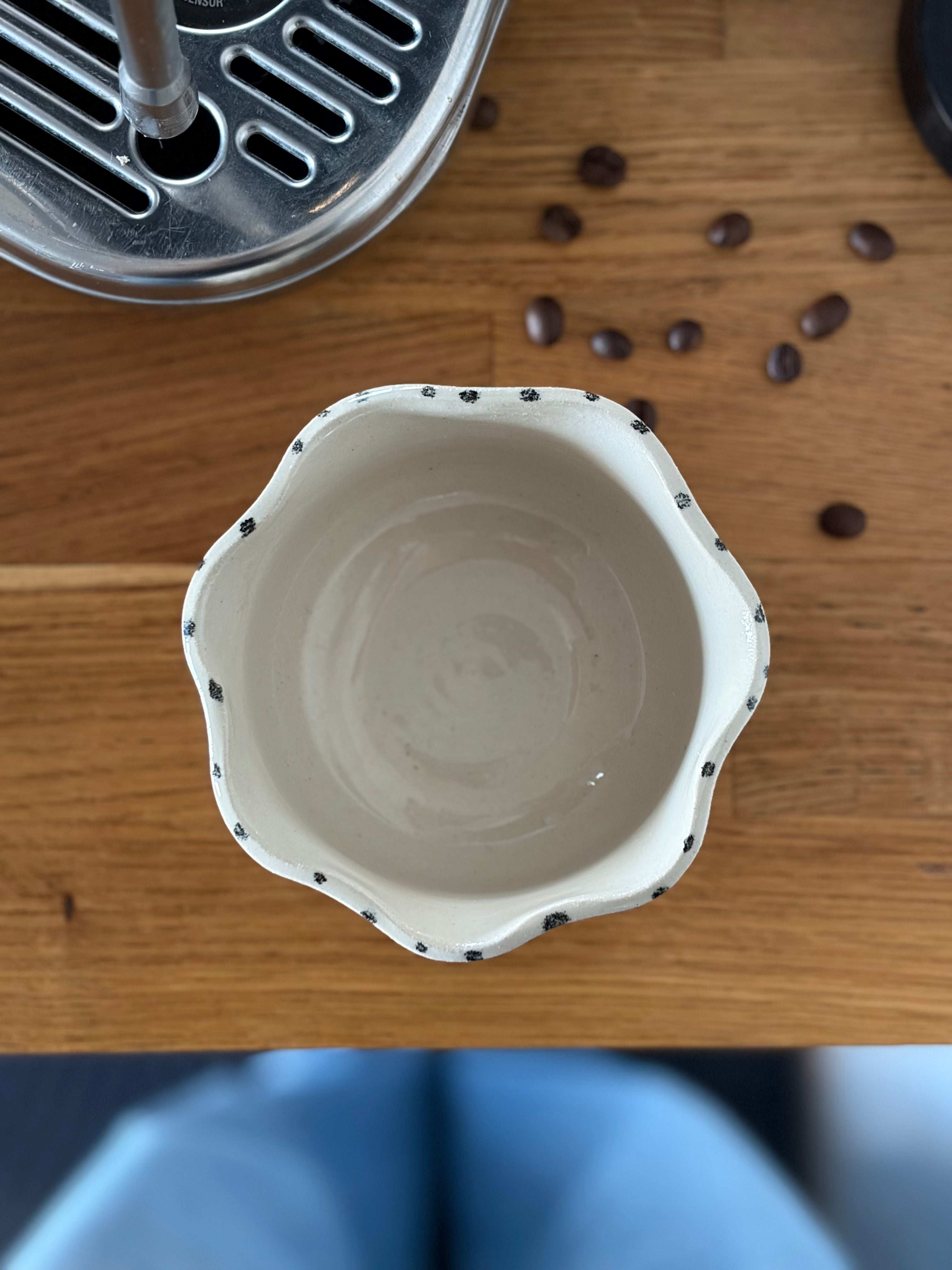 Vogelperspektive auf den Becher in Blumenform. auf Küchenzeile mit Kaffeemaschine 