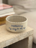 ein transparent glasierter handgemachter Keramikbecher mit einer blauen Aufschrift "overthinking my way to the top". von innen ist der Becher blau gestreift 