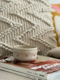 Handgedrehter Keramikbecher Tiny Hearts Cup mit kleinen roten Herzchen, auf Magazin vor gewebtem Textil-Hintergrund
